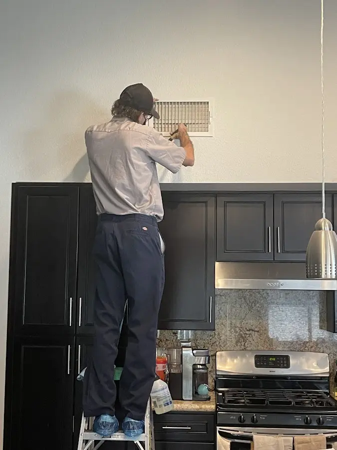 Technician inspecting an air vent during HVAC service in Johnstown
